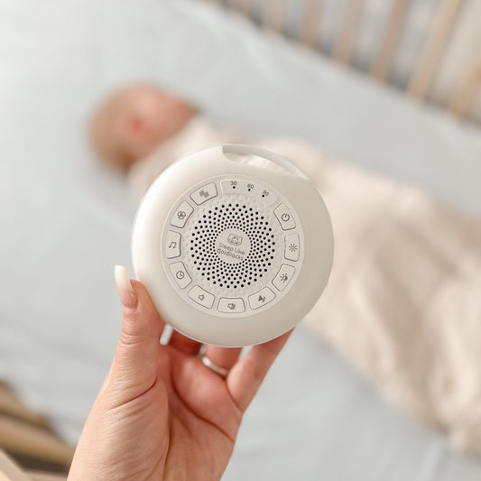 Sound Sleeper portable white noise shown above baby in cot