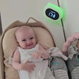 Smiling baby lying beside sleep sacks, with the Sleep Like Goldilocks thermometer showing TOG guidance on the wall